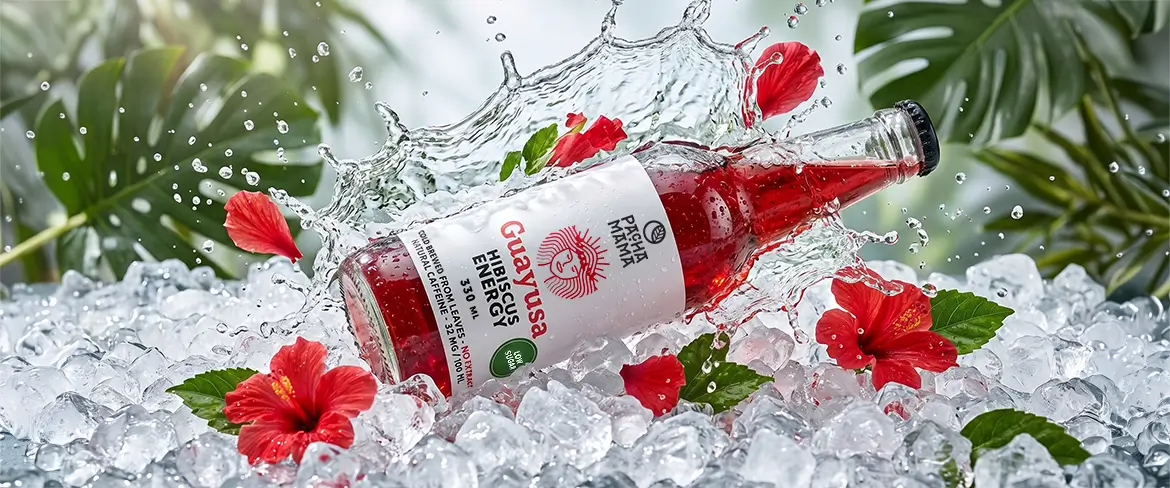 Guayusa Pachamama Cold Brew in einer Flasche auf zerstoßenem Eis mit Hibiskusblüten.